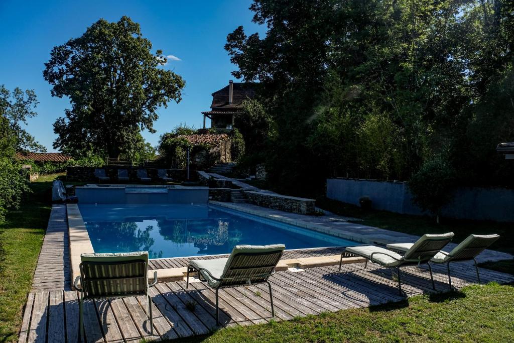 a swimming pool with chairs and a house at Les Jardins de la Contie in Lunan
