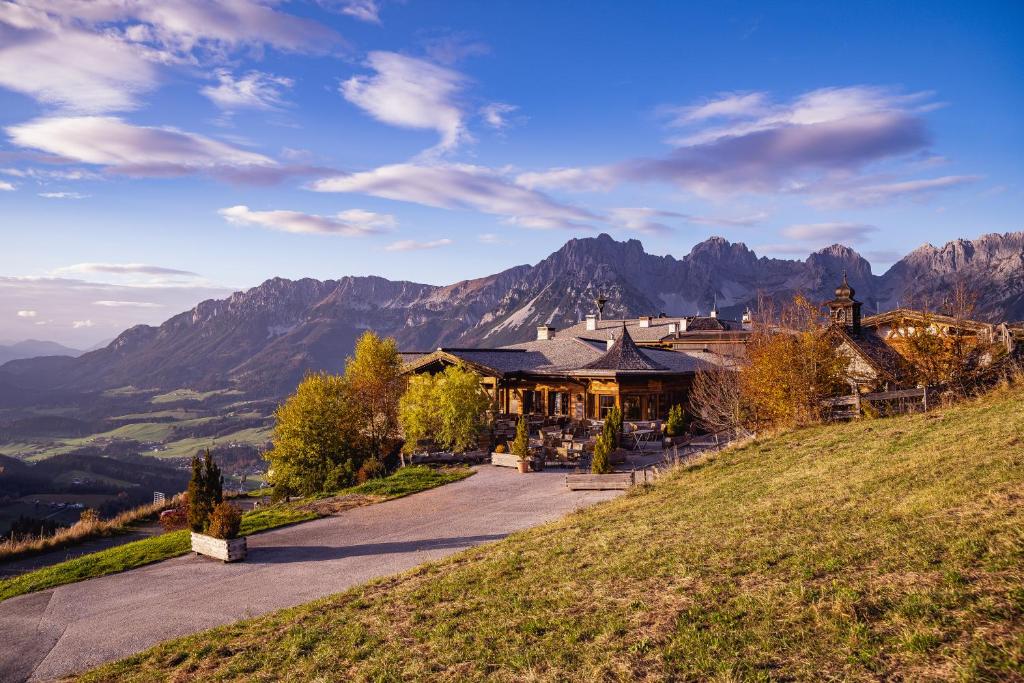 una casa en una colina con montañas en el fondo en jezz AlmResort Ellmau, en Ellmau