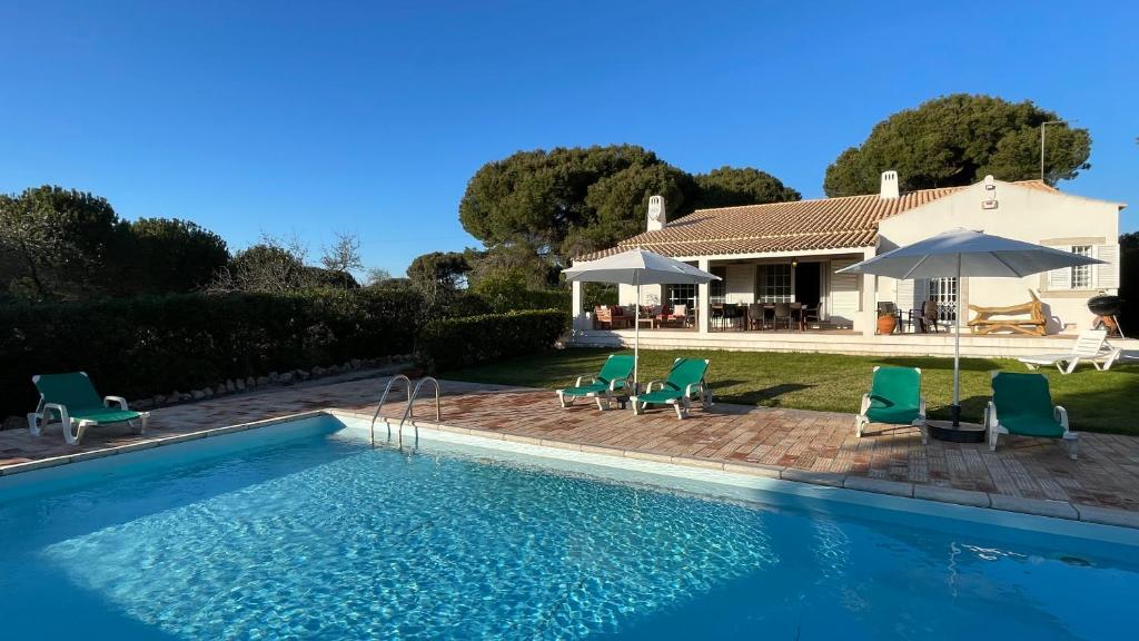 a swimming pool with chairs and a house at Sol by Check-in Portugal in Vilamoura
