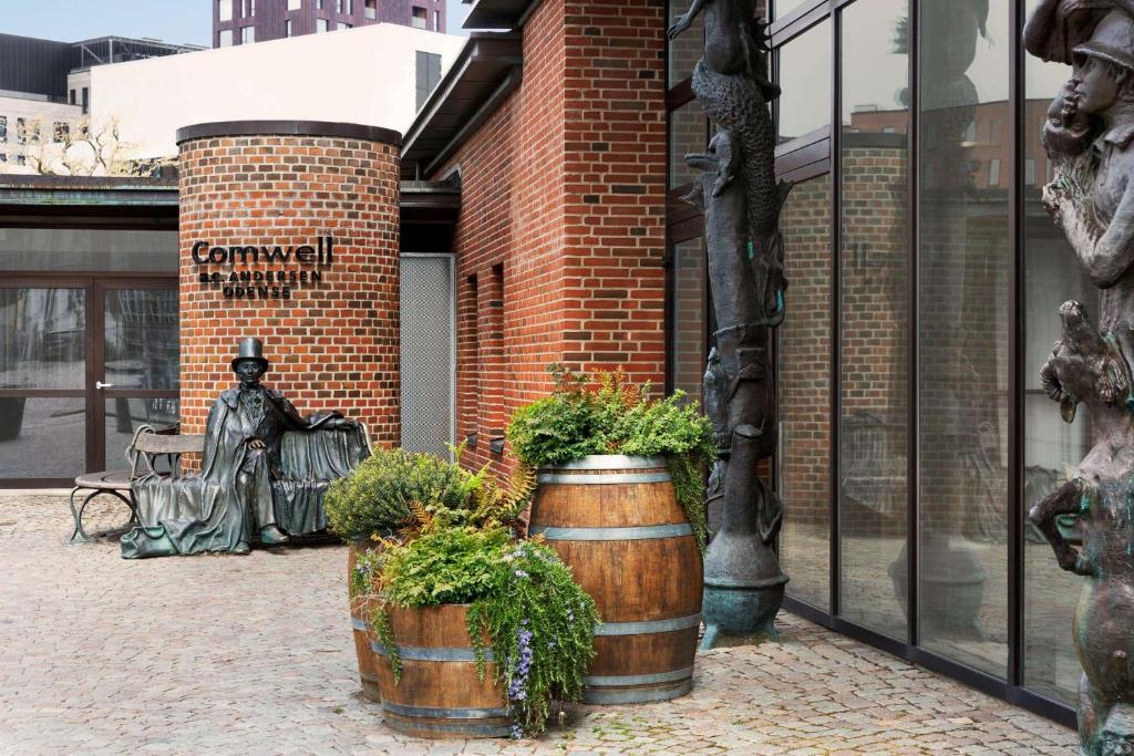 a statue of a man sitting in front of a building at Comwell H C Andersen Dolce by Wyndham in Odense