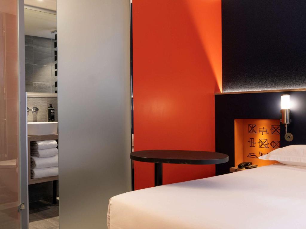 ibis Styles Bourg La Reine في بور-لا-رين: غرفة فندقية بسرير وطاولة صغيرة