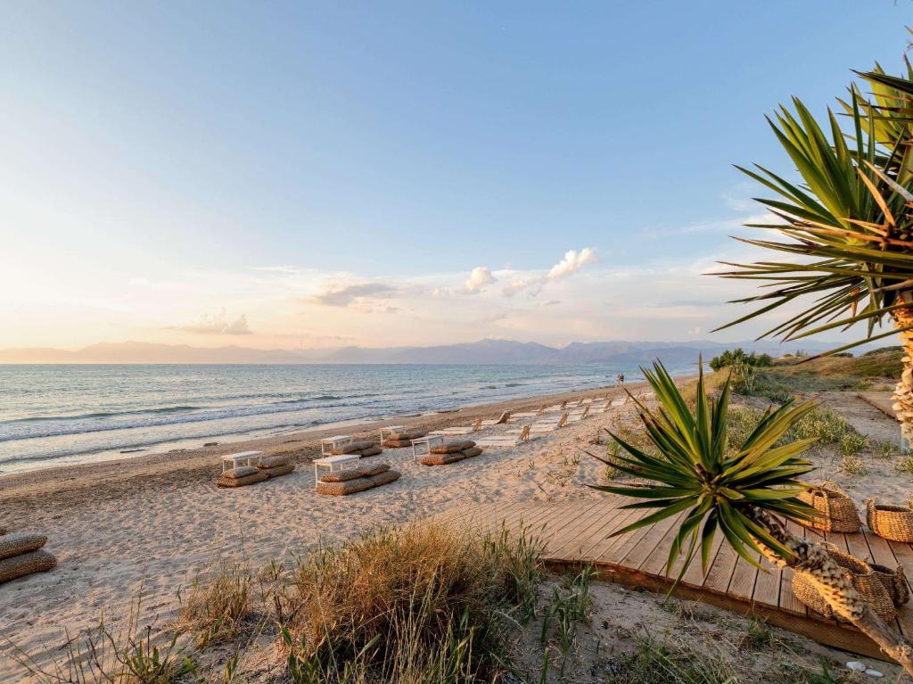 uma praia com espreguiçadeiras e o oceano em Grecotel-LUXME Costa Botanica em Acharavi