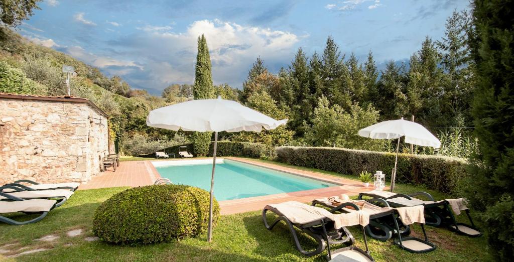 einen Pool mit Sonnenschirmen und Stühlen neben einem Pool in der Unterkunft Casetta di Butia, Glicine Apartment in Borgo a Mozzano