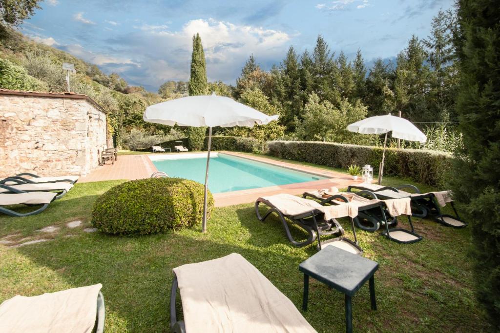 einen Pool mit Stühlen und Sonnenschirmen neben in der Unterkunft Casetta di Butia, Gelsomino Apartment in Borgo a Mozzano