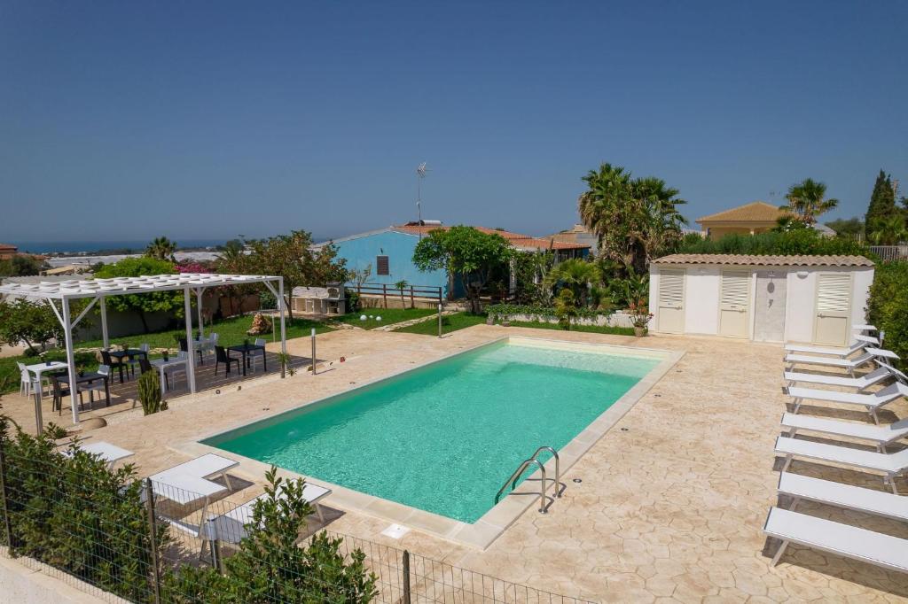 einen Pool mit Stühlen, einen Tisch und ein Haus in der Unterkunft B&B Villa Francesco in Marina di Ragusa