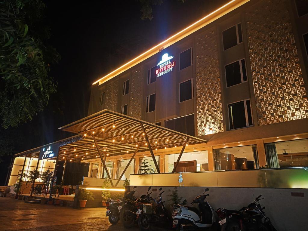 a building with motorcycles parked in front of it at night at Hotel Ruturaj Regency in Dhule