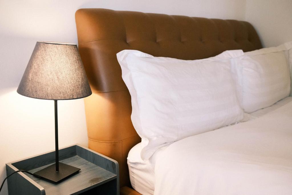 a bed with white pillows and a lamp on a night stand at Jiufen Breeze 九份惠風民宿ｌ6人包棟小屋 in Jiufen