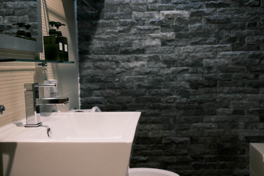 a bathroom with a sink and a brick wall at Jiufen Breeze 九份惠風民宿ｌ6人包棟小屋 in Jiufen