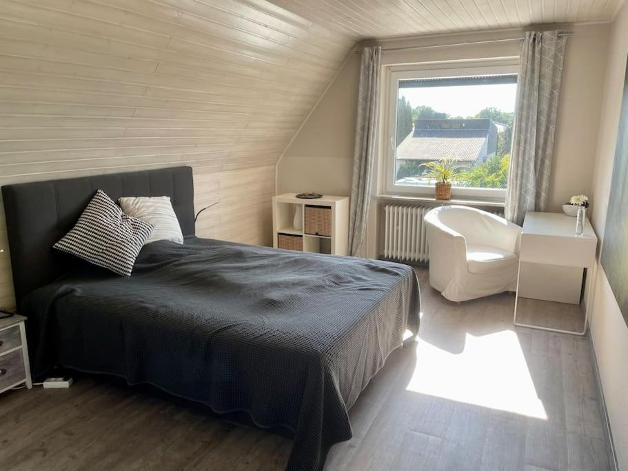 a bedroom with a bed and a window and a chair at Dein idyllisches Zuhause auf Zeit in Norderstedt in Norderstedt