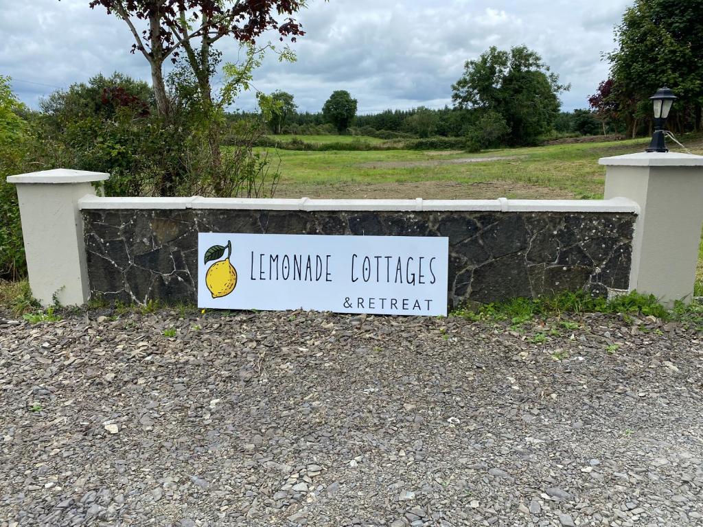 a sign on a stone wall with a sign for le lemon contractorsagent at Lemonade cottages in Kilmurry McMahon