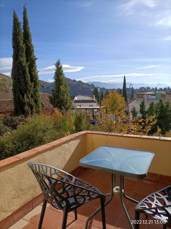 a table and chairs on a balcony with a view at Nasrid Generalife - Carmen con patio ajardinado y vistas panorámicas in Granada