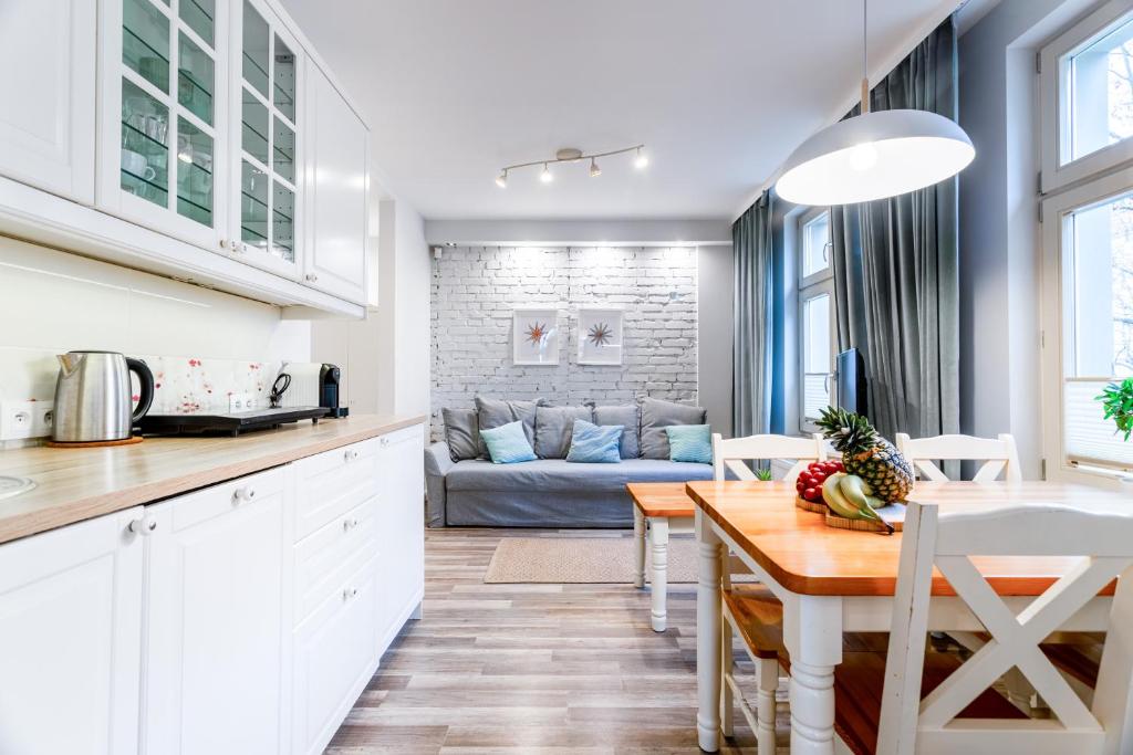 a kitchen and living room with a table and a couch at Victus Apartamenty, Villa Haffnera in Sopot