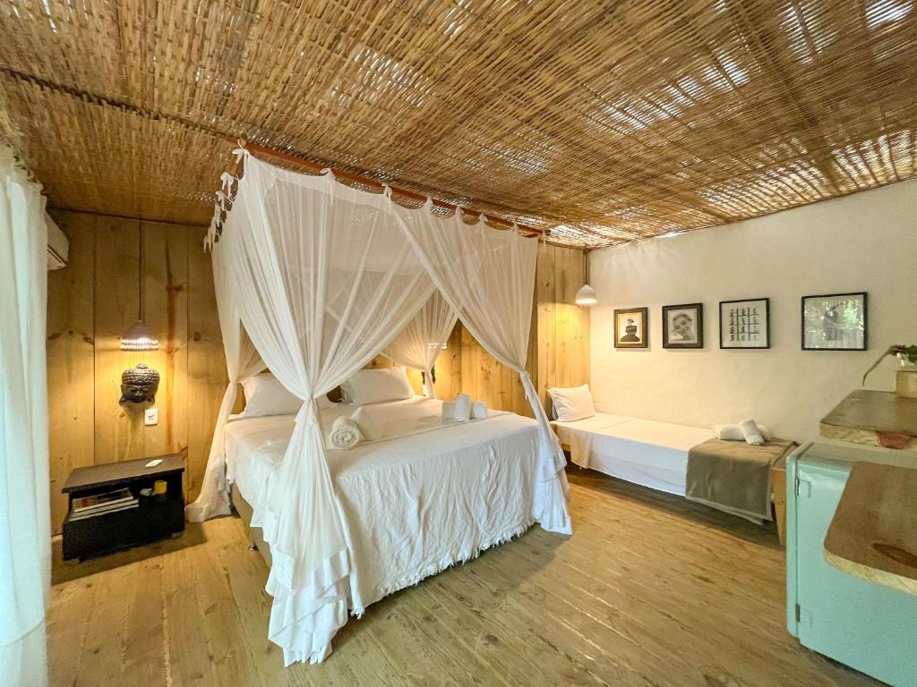 a bedroom with a bed with a mosquito net at Vila Botanika Caraíva in Caraíva