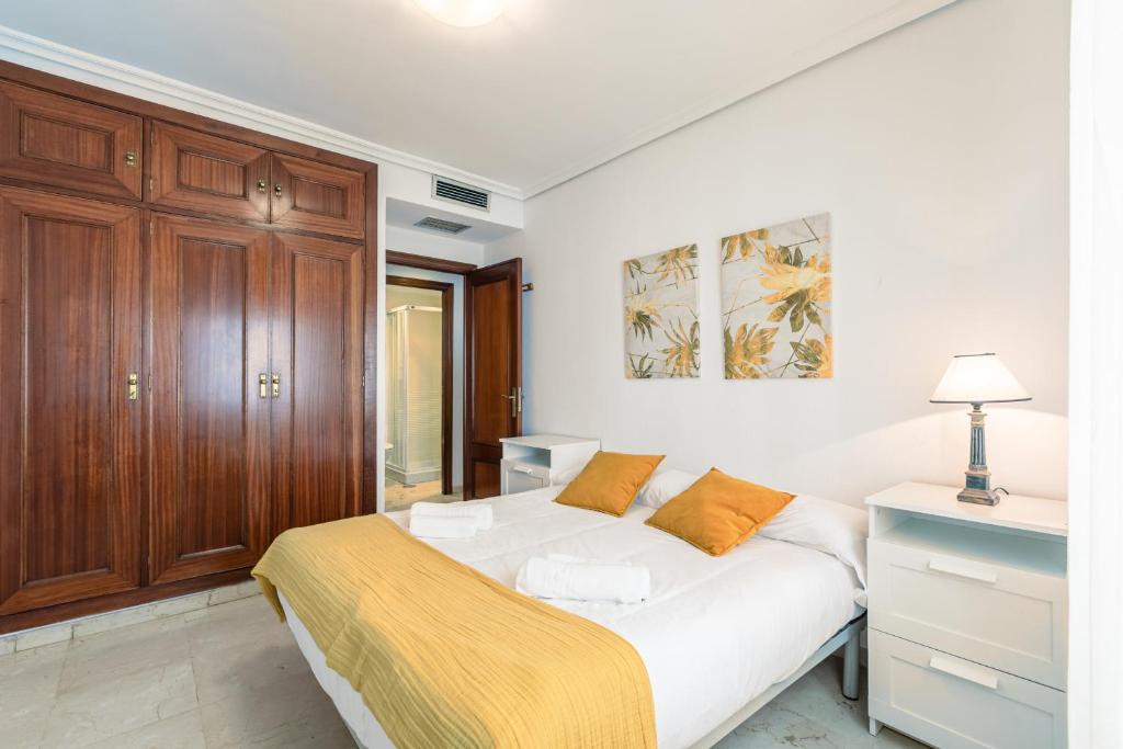 sypialnia z białym łóżkiem i drewnianą szafką w obiekcie Green- Apartments Las Setas w Sewilli