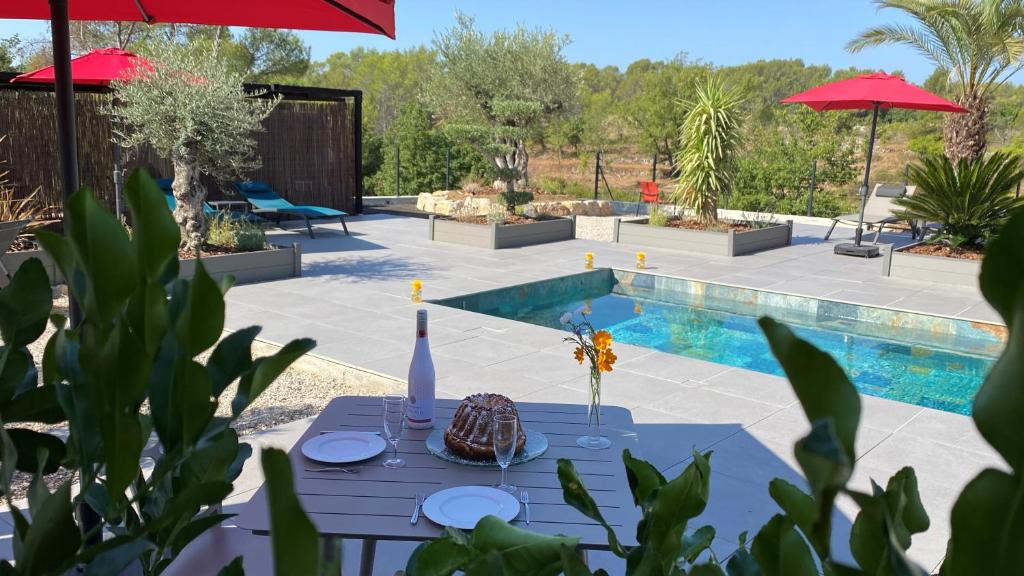 a blue table with a bottle of wine on it next to a pool at LES ROCHES DE BAUDISSET in Saint-Paul-en-Forêt