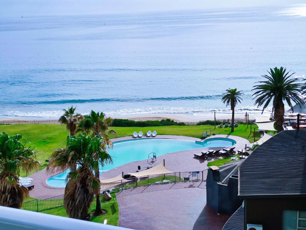 uma vista para uma piscina e para o oceano em 501 Beach Club em Mossel Bay