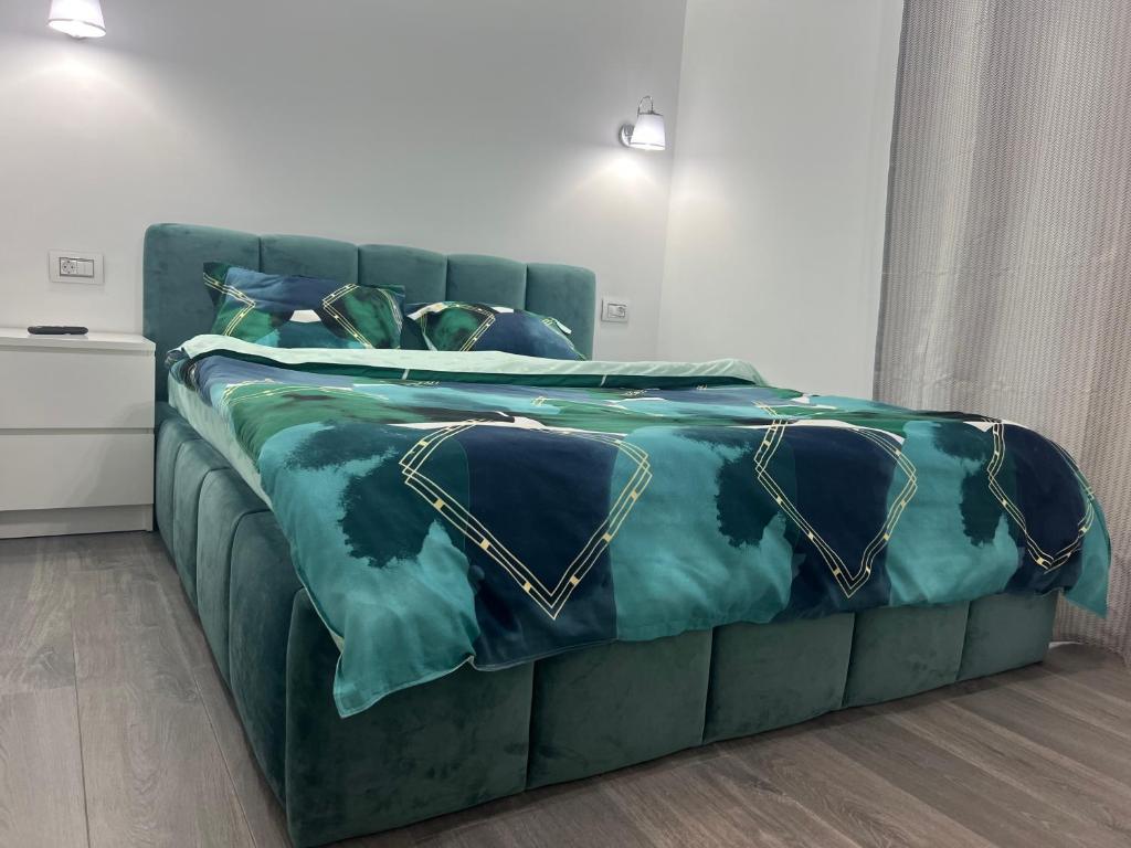 een groen bed met blauwe lakens en kussens bij Apartament Otopeni lângă parc in Otopeni