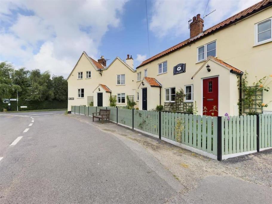 uma fila de casas com uma cerca ao lado de uma rua em Two Bedroom Cottage (rural setting with good Access links) em Grantham