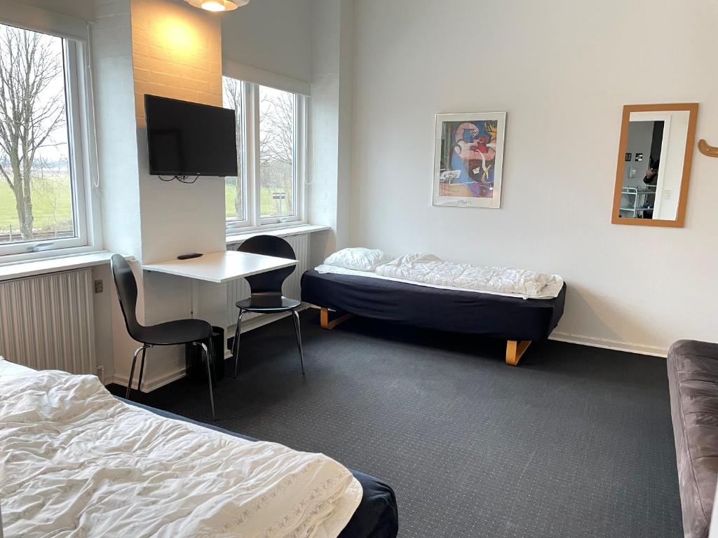 a room with two beds and a desk and a tv at rooms for rent Andersen Invest in Skjern
