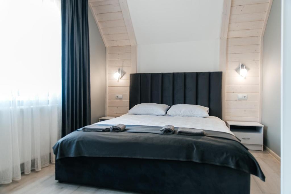 a bedroom with a large bed with a black headboard at Апартаменти Гармонія in Mizhhirya
