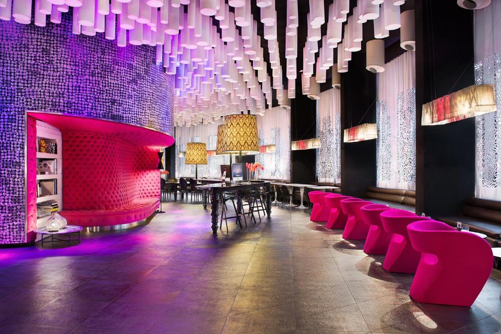 Barceló Raval في برشلونة: غرفة طعام مع كراسي وردية وإضاءة أرجوانية