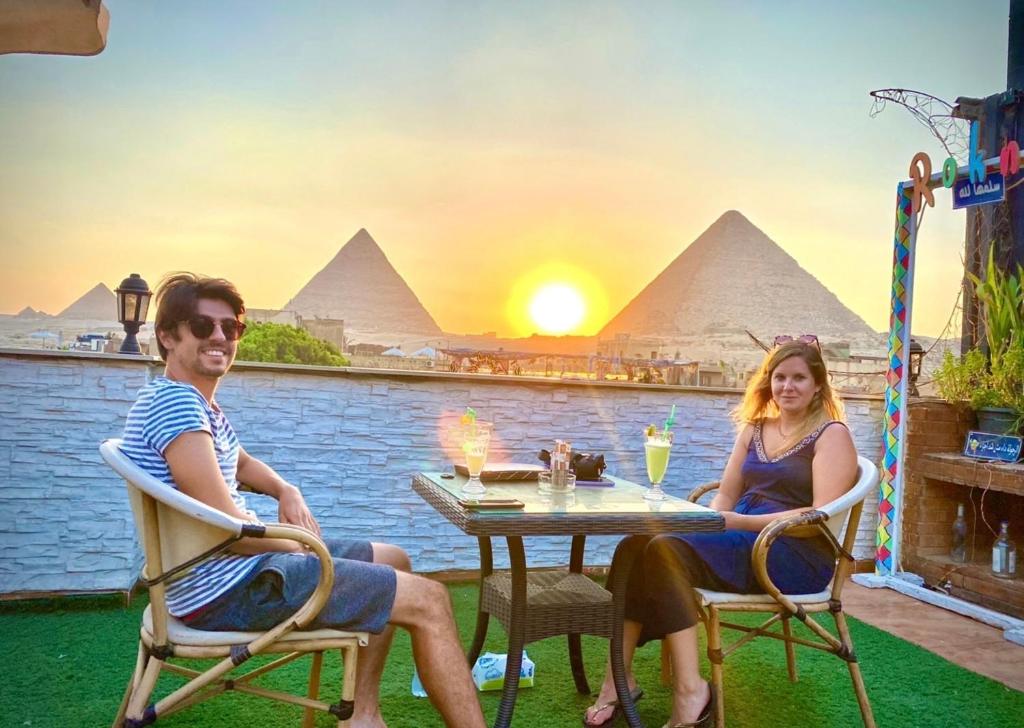 dwoje ludzi siedzących przy stole przed piramidami w obiekcie Cheops Pyramids Inn w Kairze