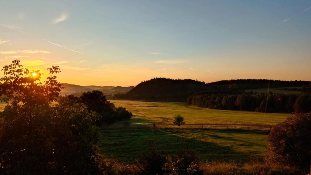 un coucher de soleil au-dessus d'un champ et un coucher de soleil en arrière-plan dans l'établissement Apartmány Skala, à Příbram