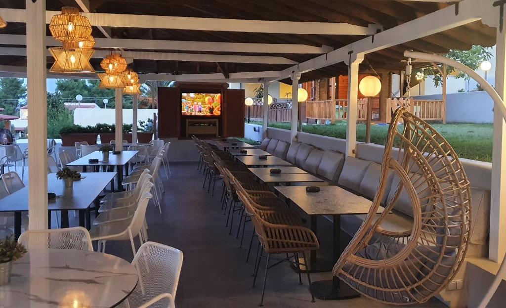 a restaurant with tables and chairs and a television at Palladium Hotel in Kriopigi