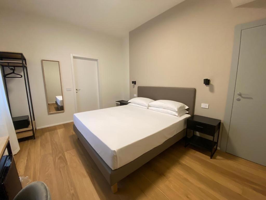 a bedroom with a large white bed and a mirror at FORESTERIA DANSI in Varese