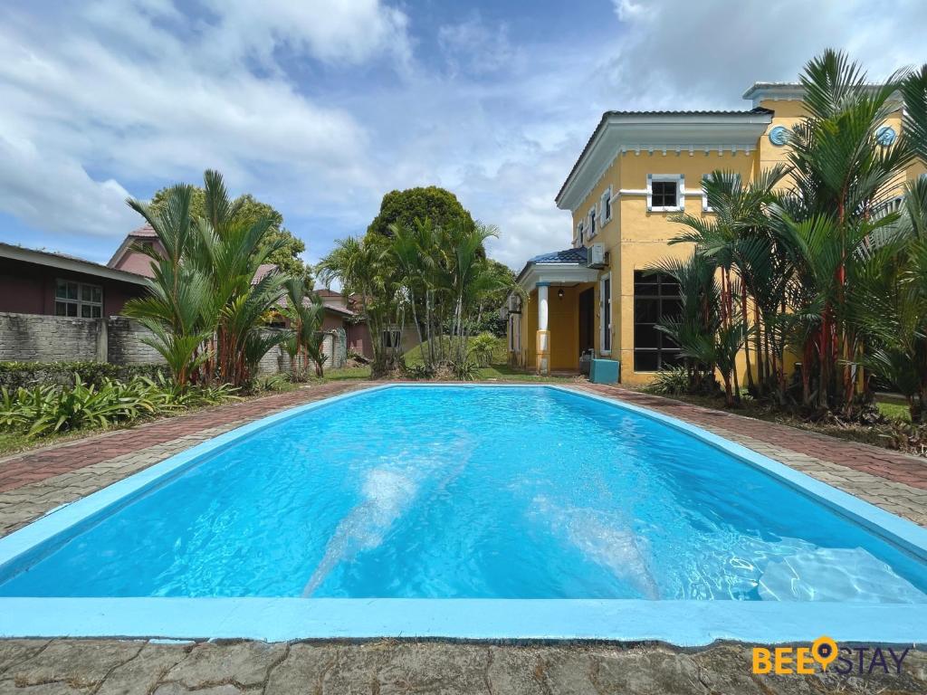 a large blue swimming pool in front of a house at Afamosa Villa with private pool by BeeStay in Kampong Alor Gajah