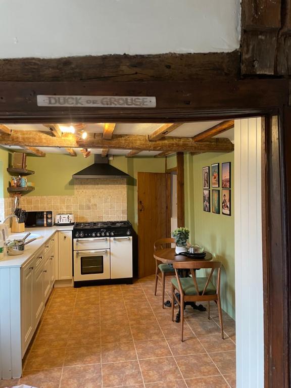 a kitchen with a table and a stove top oven at Arms Cottage in Bridge