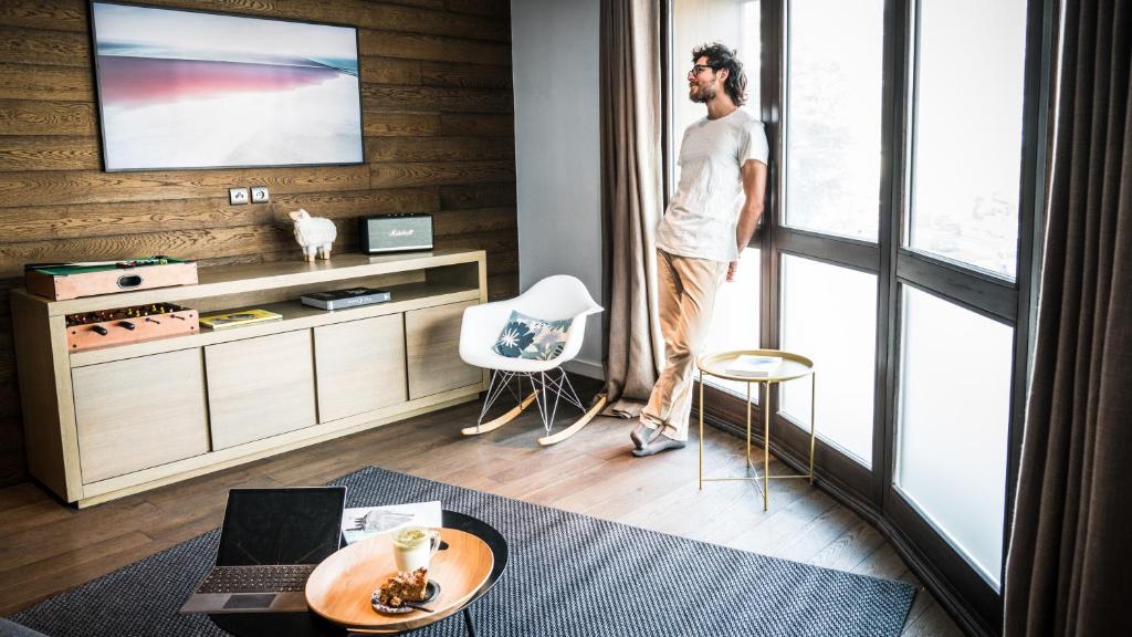een man in een woonkamer die uit het raam kijkt bij Appartement Relax in Bourg-Saint-Maurice