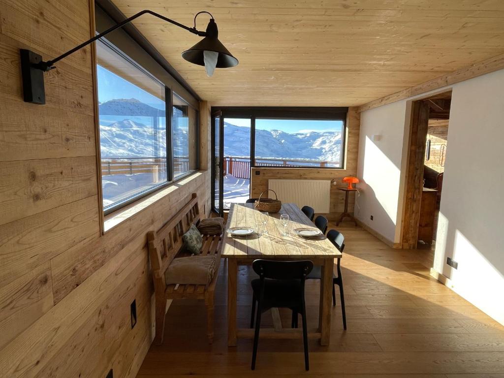 a dining room with a table and some windows at Penthouse au cœur de Val Thorens in Val Thorens