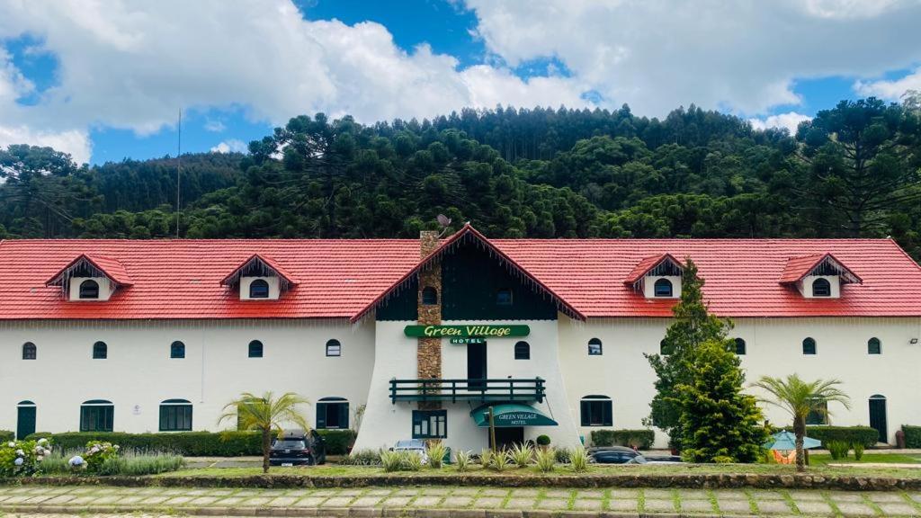 a large white building with a red roof at Green Village Hotel in Monte Verde