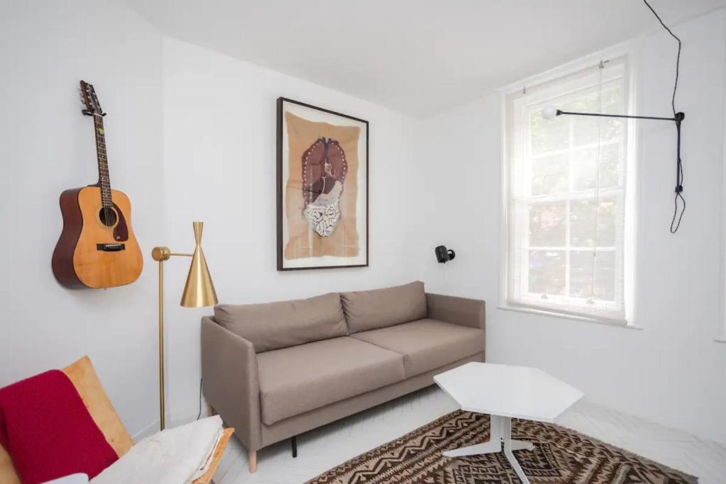 uma sala de estar com um sofá e uma guitarra na parede em Stylish and Unique 1 Bedroom flat in Shoreditch em Londres