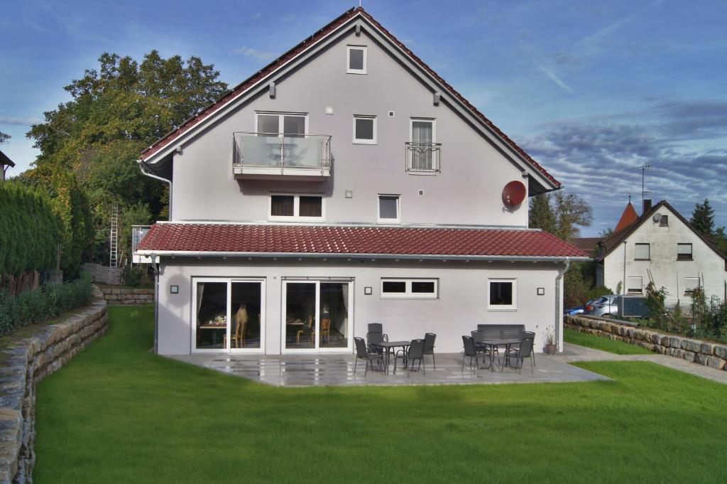 a white house with tables and chairs on a lawn at Gästehaus Winzerhof am Schlierbach 