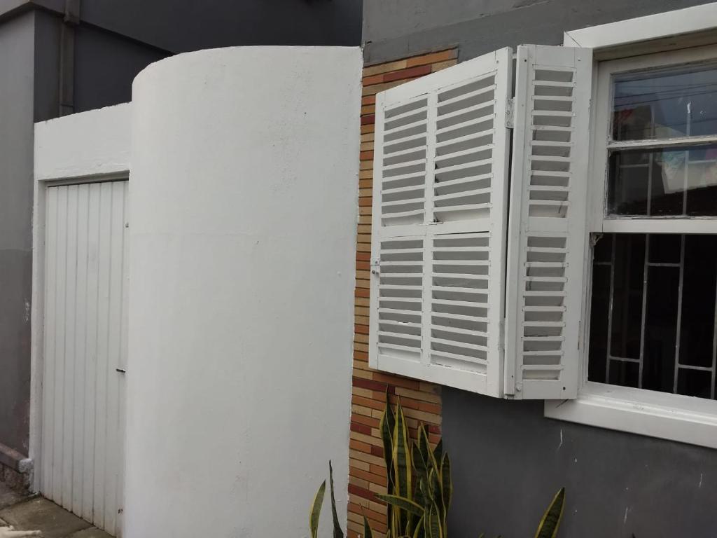 een raam met witte luiken aan de zijkant van een gebouw bij ANNANDA in Florianópolis
