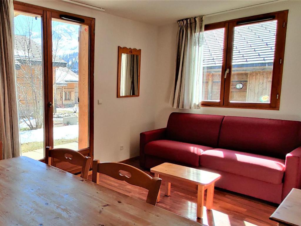 a living room with a red couch and a table at Chalet Le Dévoluy, 3 pièces, 6 personnes - FR-1-504-493 in Superdevoluy