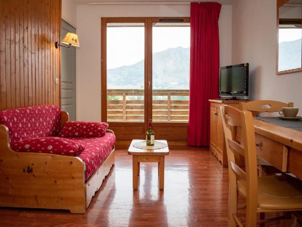 a living room with a red couch and a television at Appartement Le Dévoluy, 2 pièces, 4 personnes - FR-1-504-561 in Superdevoluy