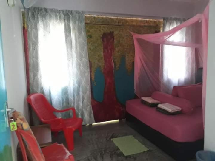 a bedroom with a pink bed and a red chair at Tahan Guest House in Kuala Tahan