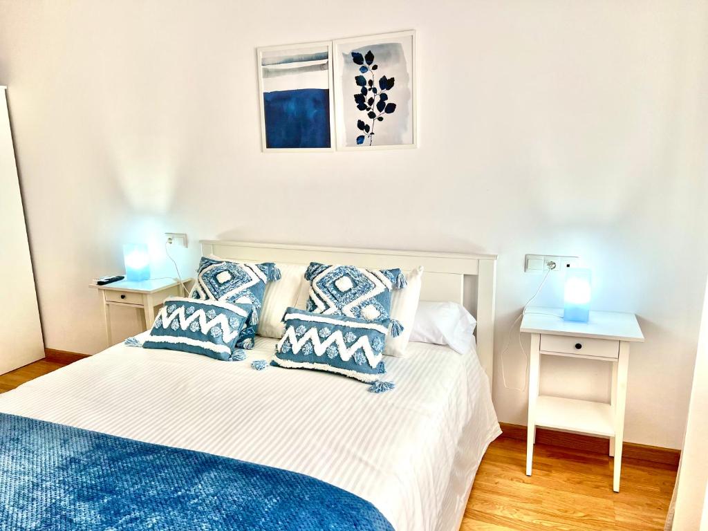 a bedroom with a bed with blue pillows and a window at Apartamento Mirando al Guadiana Centro in Ayamonte