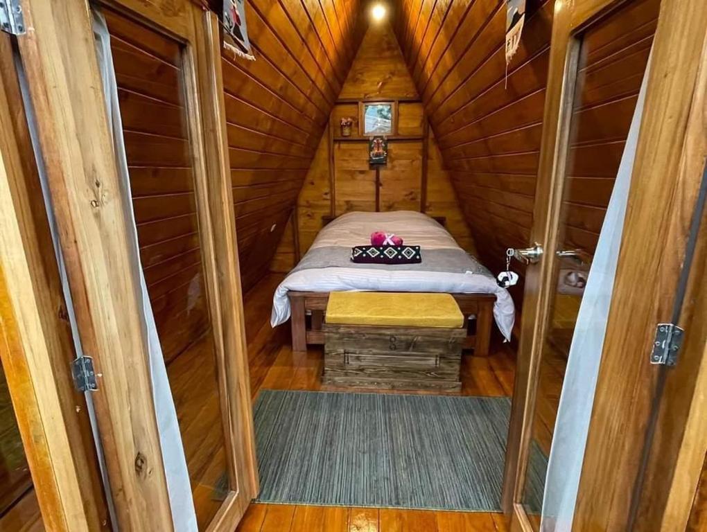 a small room with a bed in a wooden cabin at Glamping El Reencuentro in Machachi