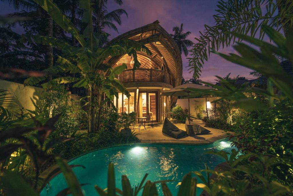a villa with a swimming pool in a garden at night at Kayuma Villas Lombok in Selong Belanak
