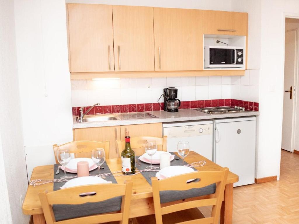 a kitchen with a table with a bottle of wine at Appartement Puy-Saint-Vincent, 2 pièces, 4 personnes - FR-1-504-340 in Puy-Saint-Vincent