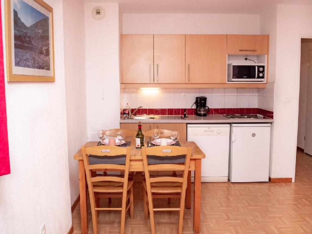 a small kitchen with a wooden table and chairs at Appartement Puy-Saint-Vincent, 2 pièces, 4 personnes - FR-1-504-340 in Puy-Saint-Vincent