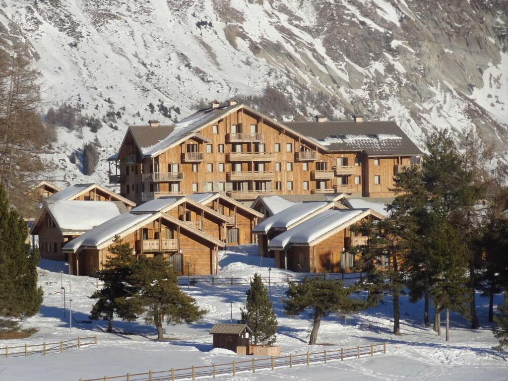 un grand bâtiment en bois dans la neige avec une montagne dans l'établissement Chalet mitoyen duplex 3 pièces, 6 pers, Résidence Le Hameau du Puy, piscine, proche pistes - FR-1-504-448, à Superdevoluy