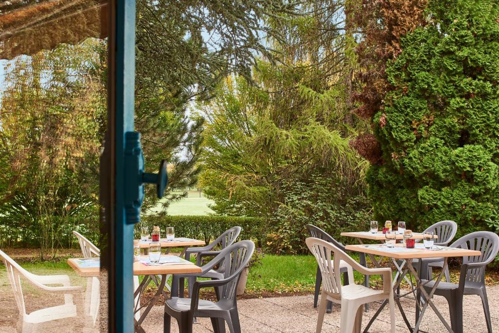 una fila de mesas y sillas en un jardín en Kyriad Direct Epinal, en Épinal