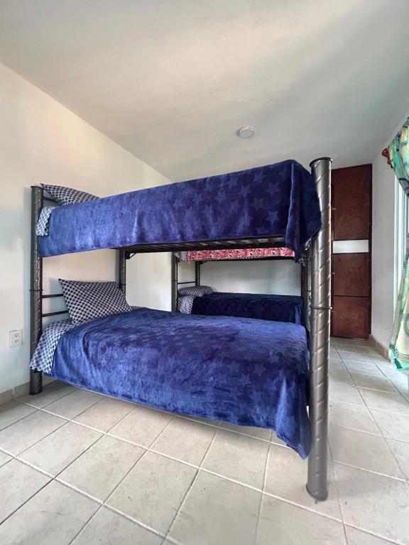 a bedroom with two bunk beds with blue sheets at Casa Machtiani in Xicotepec de Juárez
