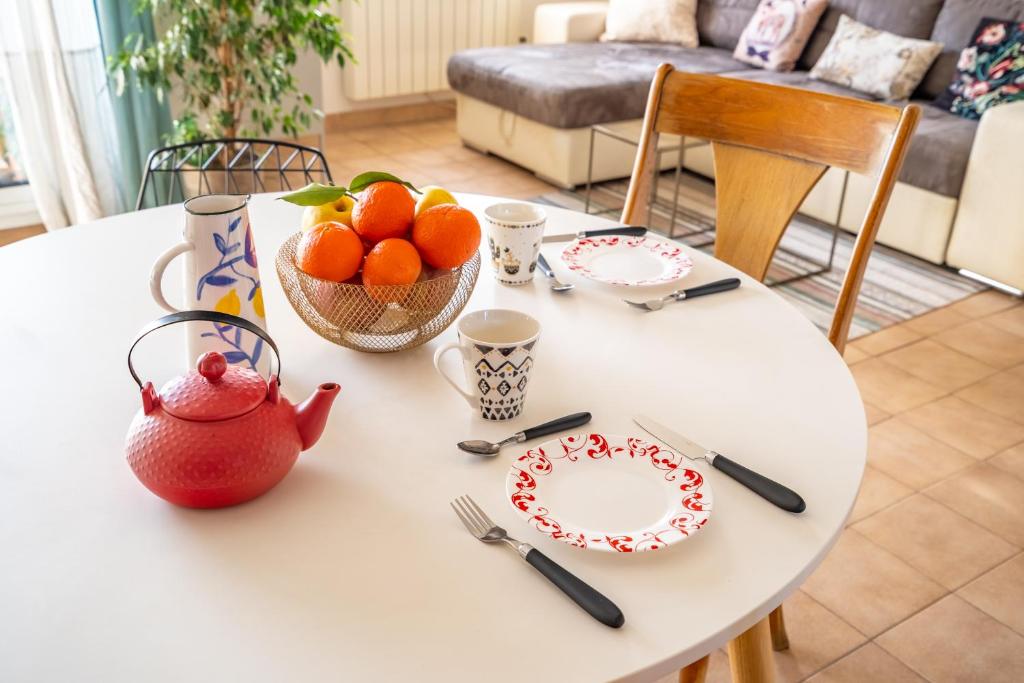 a white table with a bowl of oranges and a plate at Apt lumineux et très cosy avec balcon by Weekome in Marseille