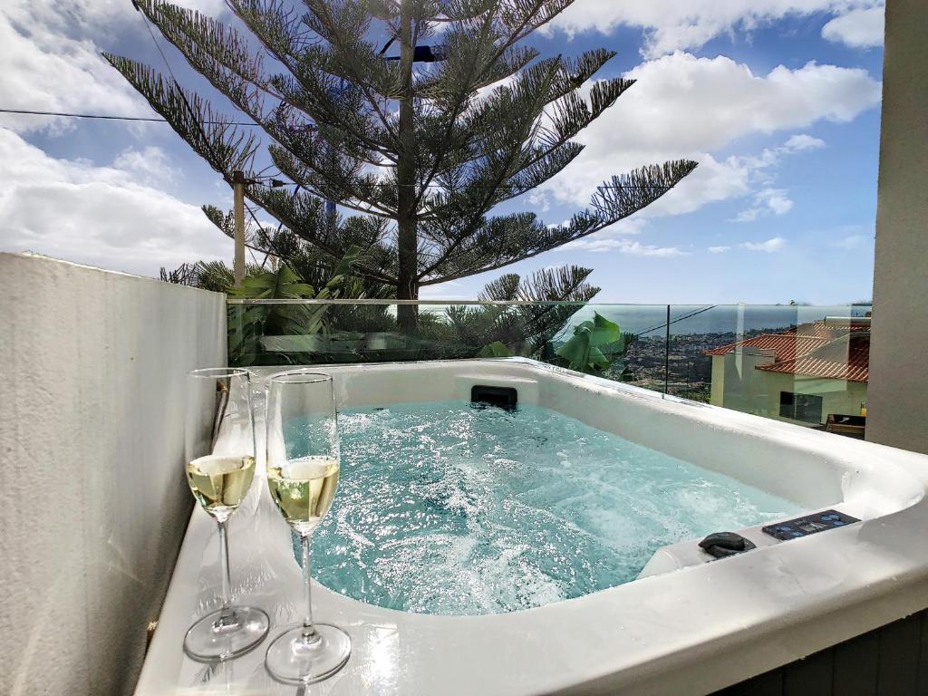 bañera de hidromasaje con 2 copas de vino y una palmera en Casa Erbozeta by LovelyStay en Funchal